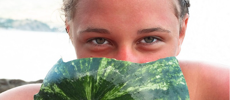 ragazza si nasconde il viso dietro anguria, vediamo solo gli occhi